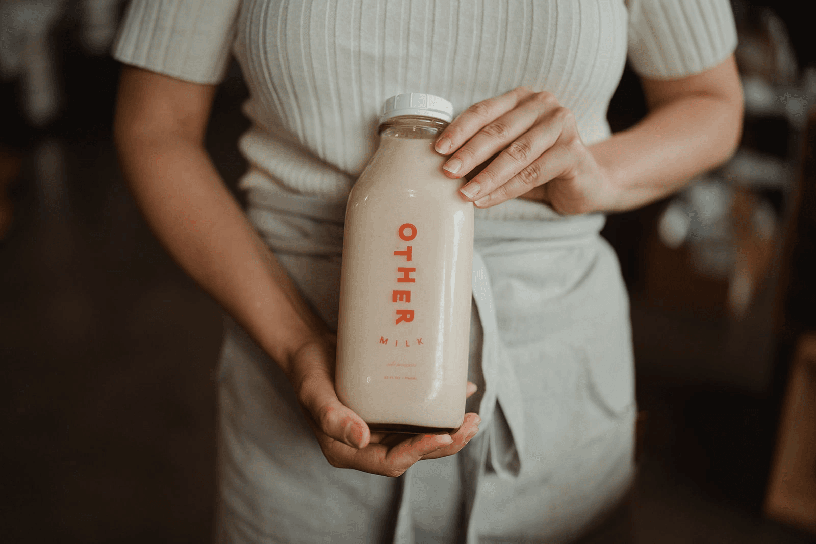 Hand holding a bottle of Other Milk pecan milk