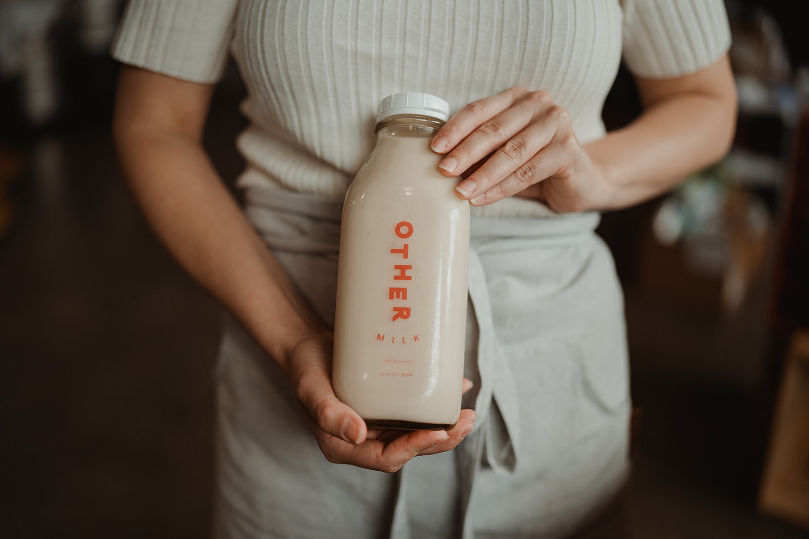 Hand holding a bottle of Other Milk pecan milk